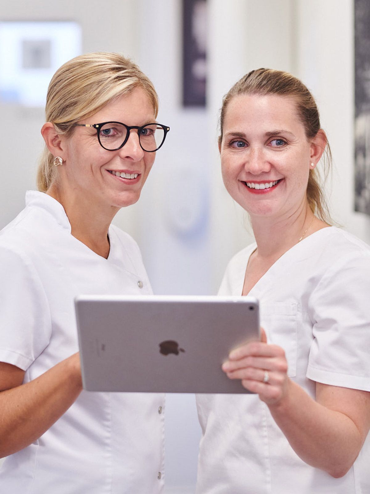 Portrait von Dr. Silke Schäfer und Dr. Sabrina Krüger im Flur besprechen Ergebnisse am Tablet